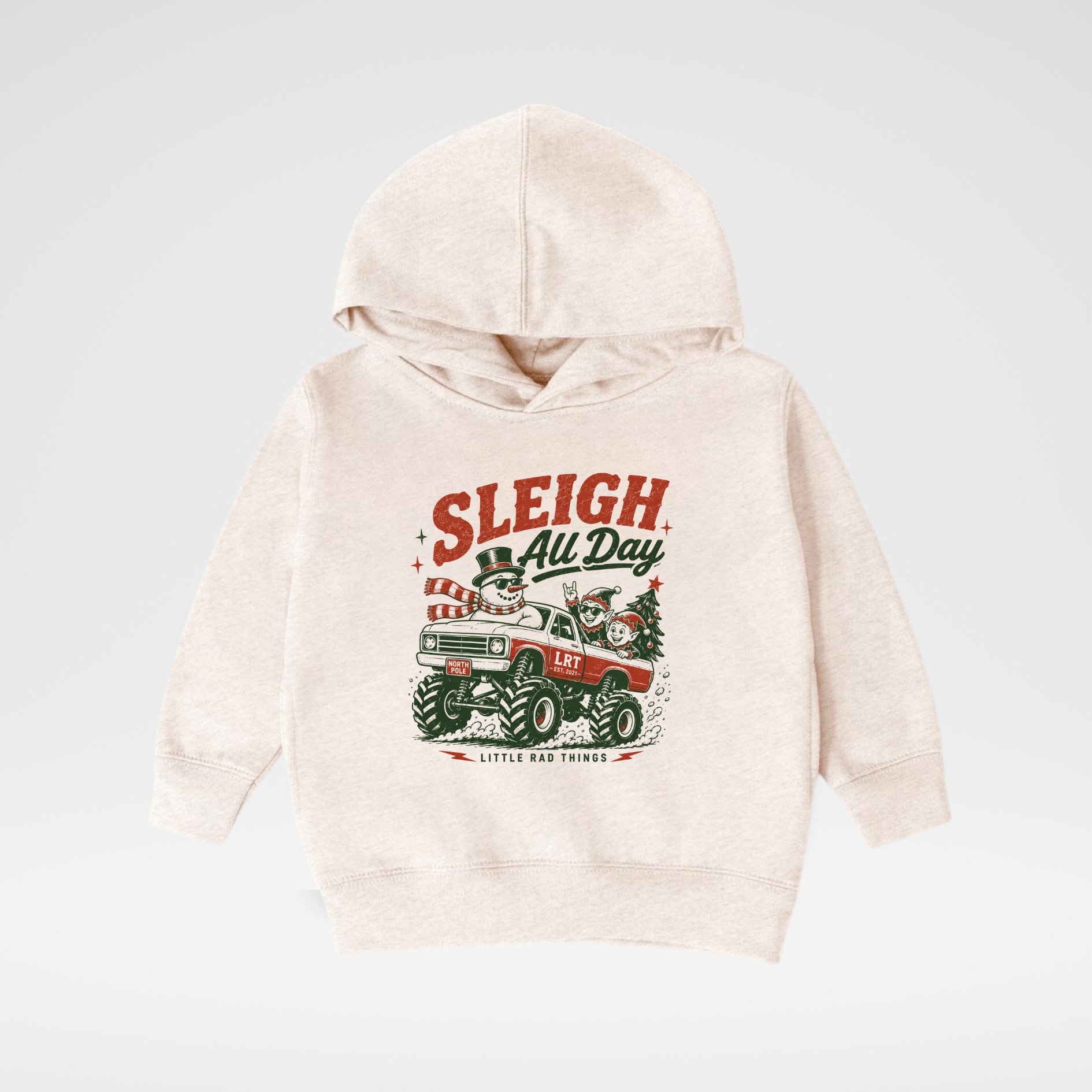 A light cream-colored hooded sweatshirt with a vintage Christmas graphic on the front featuring a red tractor, green trees, and the text 'SLEIGH All Day' and 'Little Agness Print', displayed on a neutral light gray background.