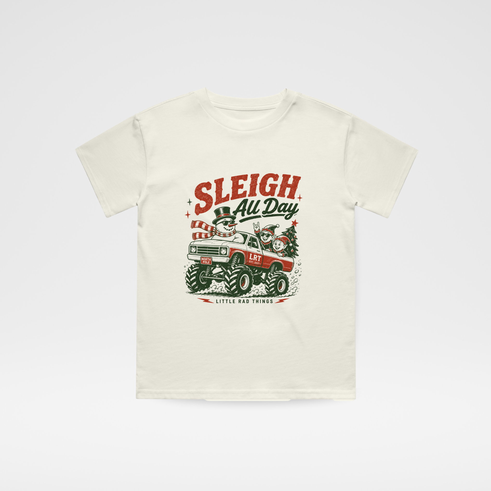 An off-white short-sleeve t-shirt with a vintage Christmas graphic on the front featuring a red and green sleigh and the text 'SLEIGH All Day' and 'Little Red Sleigh'.