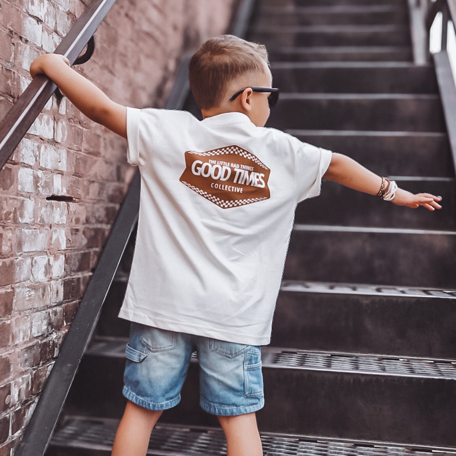 Child wearing a 'Good Time' shirt on a set of stairs.