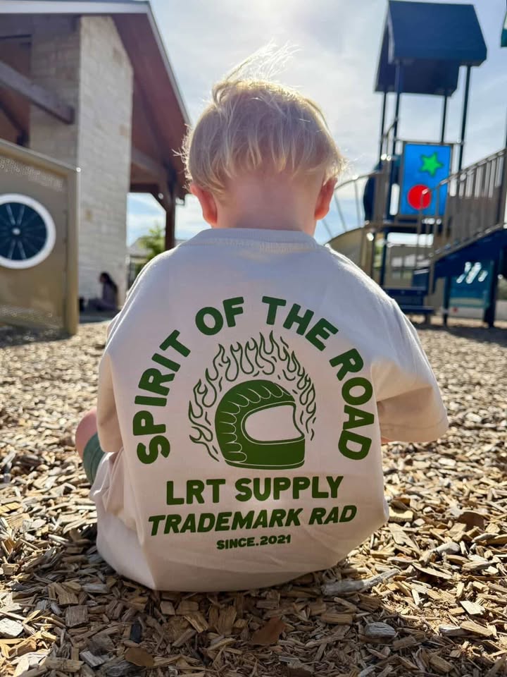 Child wearing a shirt with 'Spirit of the Road' text at a playground