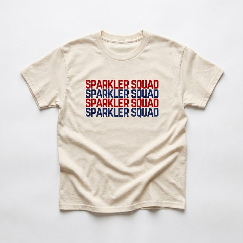 Beige t-shirt with 'Sparkler Squad' text in red, blue, and black on a white background