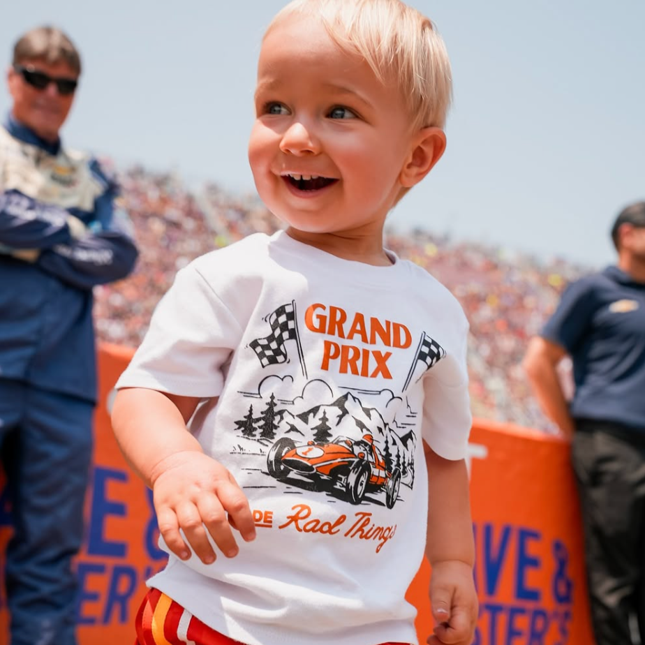 Child wearing a 'Grand Prix' t-shirt at a race track event