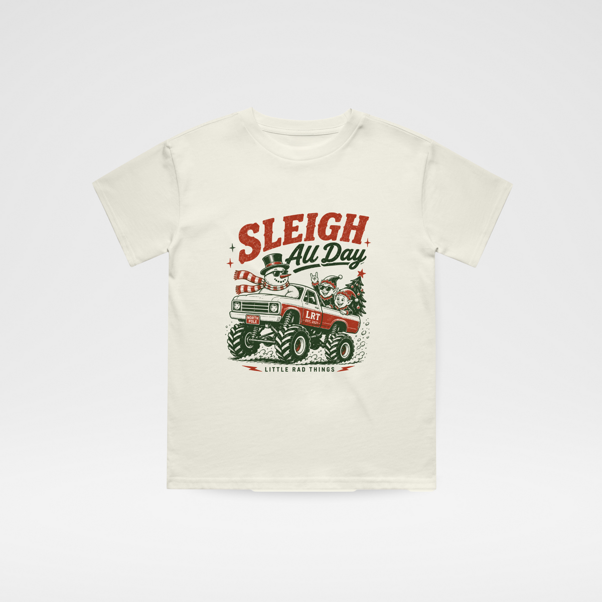 An off-white short-sleeve t-shirt with a vintage Christmas graphic on the front featuring a red and green sleigh and the text 'SLEIGH All Day' and 'Little Red Sleigh'.